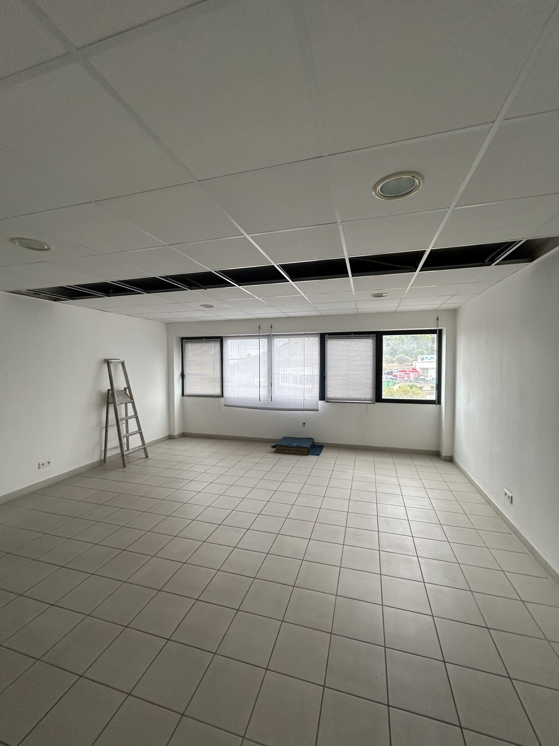 Salon cosy aux murs saumon vue plage Intérieur d'une pièce aux murs saumon clair, avec un canapé clair, un petit frigo et micro-ondes, et une porte-fenêtre donnant sur un extérieur plat et clair.